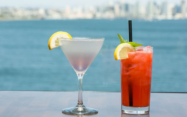 two cocktails with an ocean view behind them
