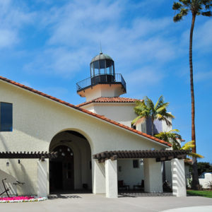 a building with a lighthouse attached and palm trees around it